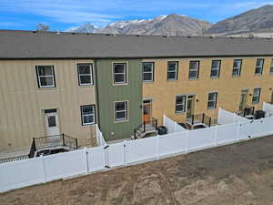 Exterior space with a mountain view, a fenced backyard, a shingled roof, and a gate