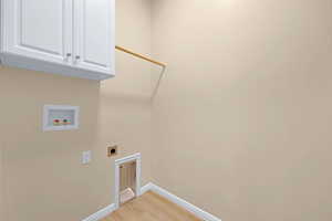 Laundry area featuring baseboards, washer hookup, light wood-style floors, hookup for an electric dryer, and cabinet space