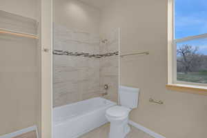 Full bath with toilet, baseboards, and bathtub / shower combination
