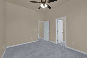 Carpeted empty room featuring baseboards and ceiling fan