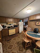 Kitchen featuring black microwave, wooden walls, range with gas cooktop, and freestanding refrigerator