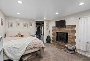 Carpeted bedroom featuring a closet, recessed lighting, and a brick fireplace