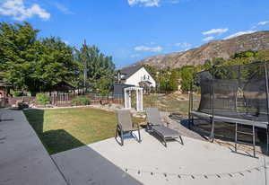 View of yard featuring a trampoline, a patio area, and a mountain view