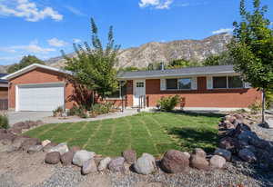 Single story home with a garage, a front yard, driveway, and a mountain view