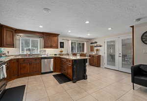 Kitchen with a peninsula, french doors, a textured ceiling, light tile patterned floors, and dishwasher