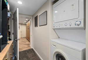 Laundry room featuring baseboards, stacked washing maching and dryer, laundry area, carpet floors, and recessed lighting