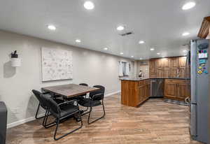 Dining room featuring light wood-style floors, bar area, baseboards, and recessed lighting