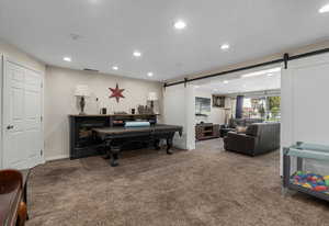 Carpeted living room featuring recessed lighting and a barn door