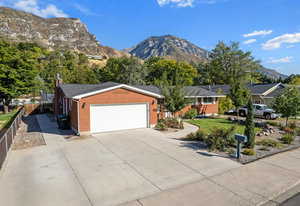 Ranch-style home with a mountain view, an attached garage, and driveway