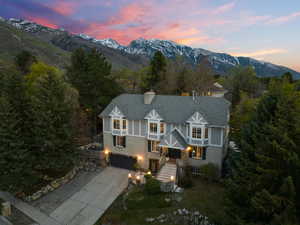 Exterior space with stone siding, concrete driveway, a chimney, an attached garage, and a mountain view