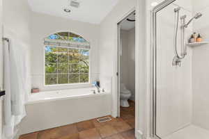 Bathroom featuring a shower stall, visible vents, toilet, and a garden tub