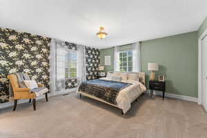 Carpeted bedroom with wallpapered walls, a textured ceiling, baseboards, and visible vents