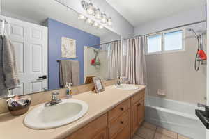 Bathroom featuring tile patterned flooring, a sink, double vanity, and shower / bath combo with shower curtain