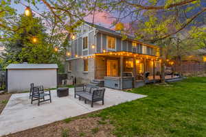 Back of house with fence, an outdoor structure, a yard, and a patio area
