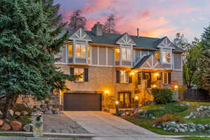 View of front of house featuring fence, a chimney, a garage, brick siding, and driveway
