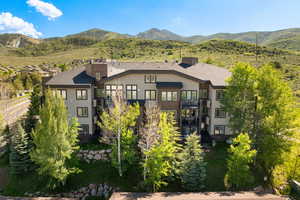 Back of property featuring a balcony, stucco siding, a mountain view, and stairway