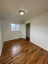 Unfurnished bedroom with wood finished floors and a closet
