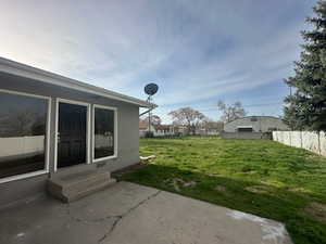 View of yard featuring entry steps, a patio area, and fence