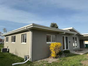 View of property exterior with central AC unit and a lawn