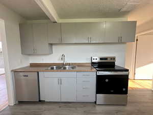 Kitchen featuring light wood-style flooring, gray cabinetry, visible vents, appliances with stainless steel finishes, and a sink