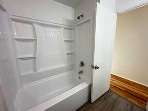 Full bath featuring wood finished floors and  shower combination
