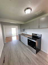 Kitchen with a sink, visible vents, light wood-style flooring, and appliances with stainless steel finishes