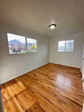 Unfurnished room with wood finished floors and a wealth of natural light