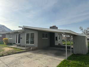 View of front of house with a carport, a mountain view, driveway, and a chimney