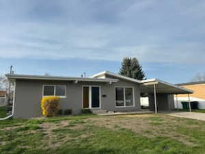 Single story home with driveway, an attached carport, and a front lawn