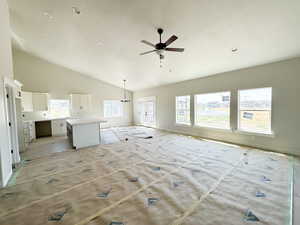 Unfurnished living room featuring a ceiling fan, a chandelier, and high vaulted ceiling