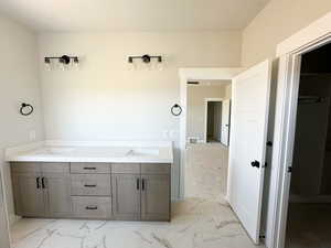 Bathroom featuring double vanity and light marble finish flooring