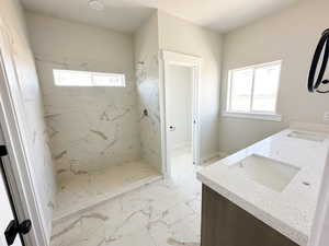 Full bath featuring light marble finish floors, a marble finish shower, and double vanity