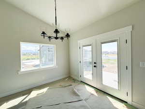Unfurnished dining area with a chandelier, french doors, and vaulted ceiling