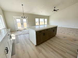 Kitchen featuring light wood-type flooring, decorative light fixtures, open floor plan, a chandelier, and light stone countertops