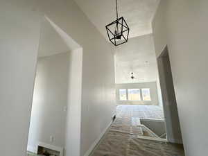 Hall with baseboards and a chandelier