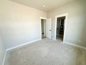 Unfurnished bedroom featuring a walk in closet and baseboards