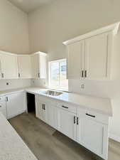 Kitchen featuring white cabinets, light stone counters, dark wood finished floors, and a high ceiling