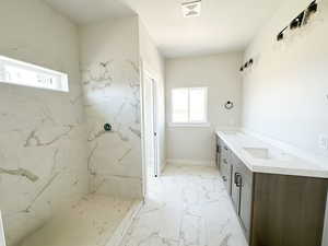 Bathroom with a marble finish shower, double vanity, healthy amount of natural light, and light marble finish flooring