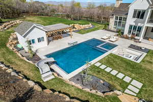 View of pool featuring a pergola, a patio area, a lawn, outdoor lounge area, and fence
