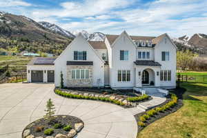 Modern farmhouse style home featuring an attached garage, driveway, fence, and a mountain view