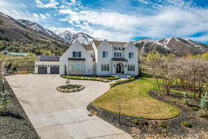 French provincial home with a front lawn, a mountain view, a garage, curved driveway, and roof mounted solar panels