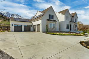 View of property exterior with fence, solar panels, driveway, roof with shingles, and a mountain view