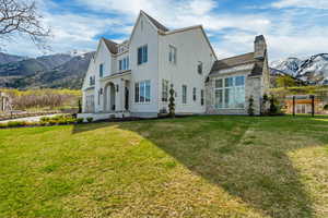 Rear view of property featuring a lawn, a chimney, fence, and a mountain view