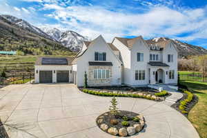 View of front of home with curved driveway, roof mounted solar panels, a mountain view, fence, and an attached garage