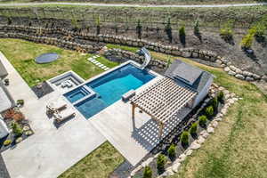 View of pool featuring a lawn, a fenced backyard, a water slide, and a patio area