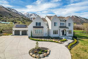 View of front of property with fence, curved driveway, a mountain view, and solar panels