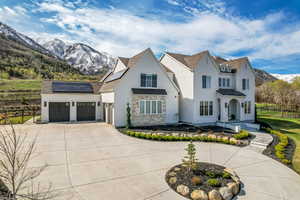 View of front of house featuring a mountain view, solar panels, driveway, fence, and a garage