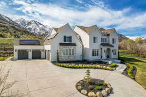 Modern farmhouse with curved driveway, an attached garage, a mountain view, fence, and solar panels