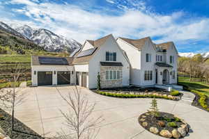 View of front of home featuring a mountain view, solar panels, concrete driveway, a garage, and a shingled roof
