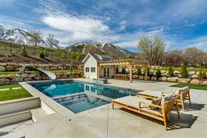View of swimming pool featuring a pergola, a water slide, an in ground hot tub, and a mountain view